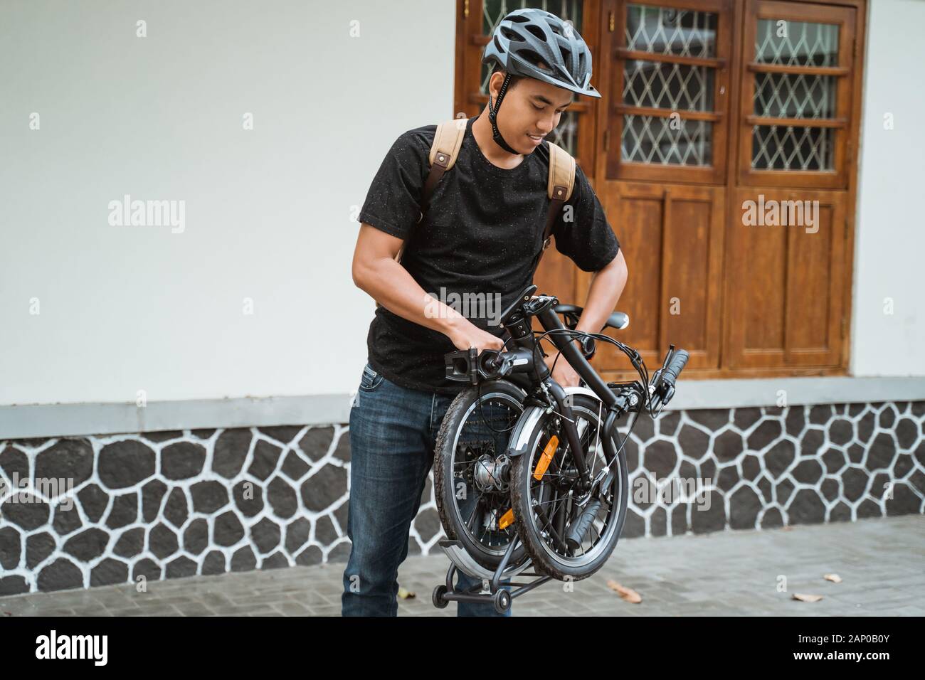 Asiatischer junger Mann, der ihr Klapprad vorbereitet Stockfoto