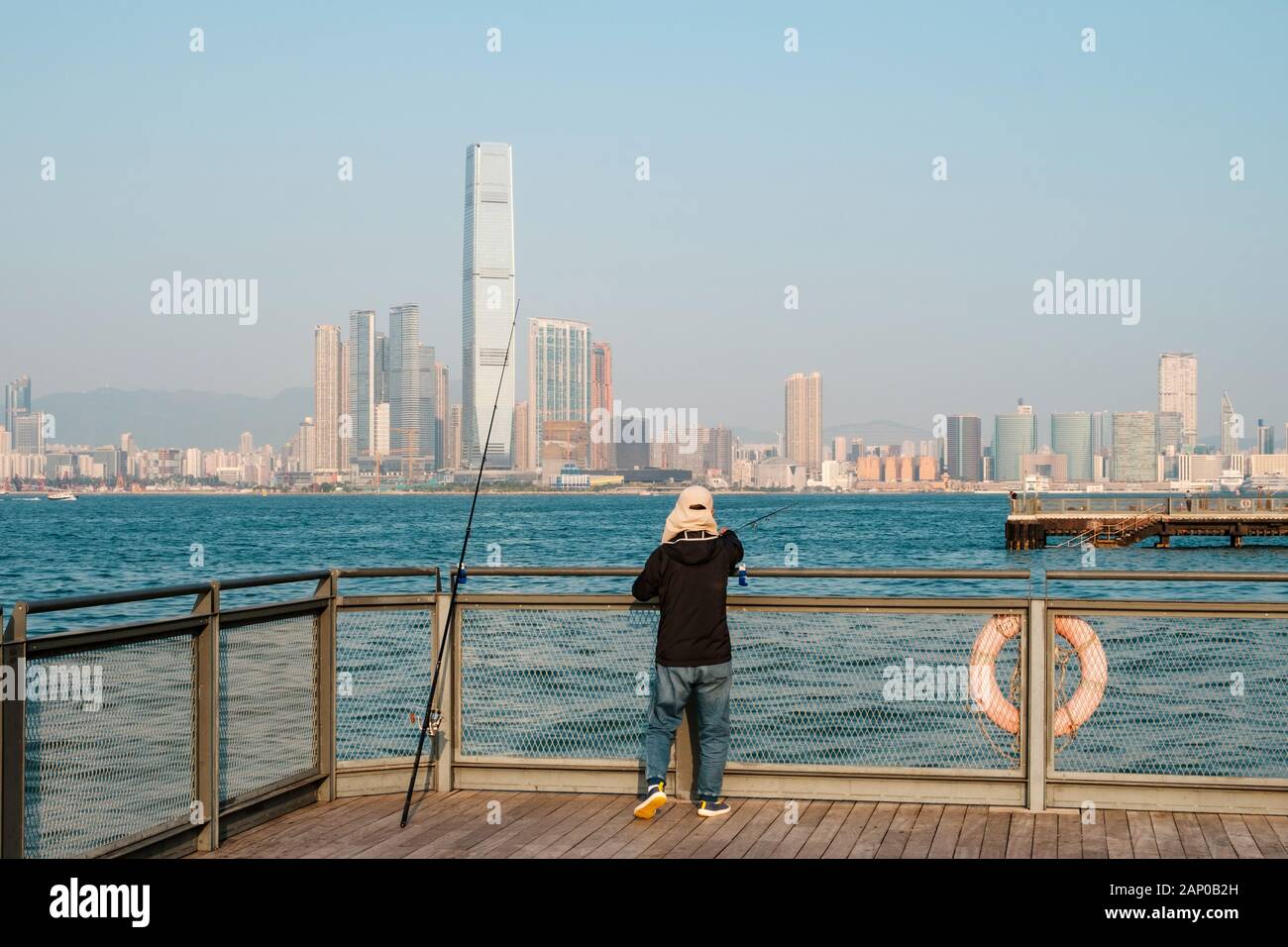 Fisher Mann mit angelrute an der Küste mit HongKong skyline Stockfoto