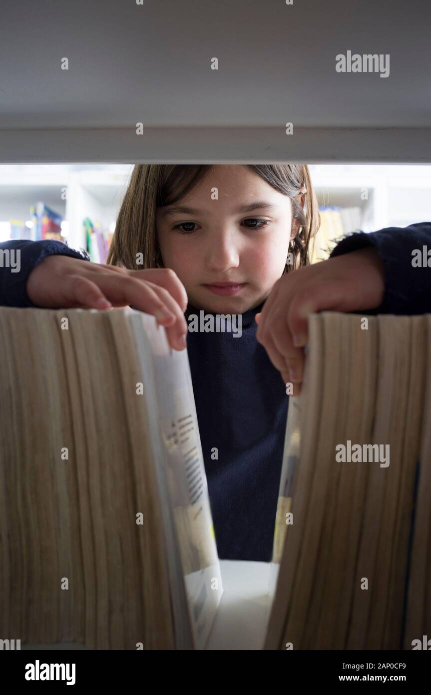 Junge Mädchen Auswahl der Bücher aus der Bibliothek Bücherregal. Kinder Kreativität und Phantasie Konzept. Stockfoto