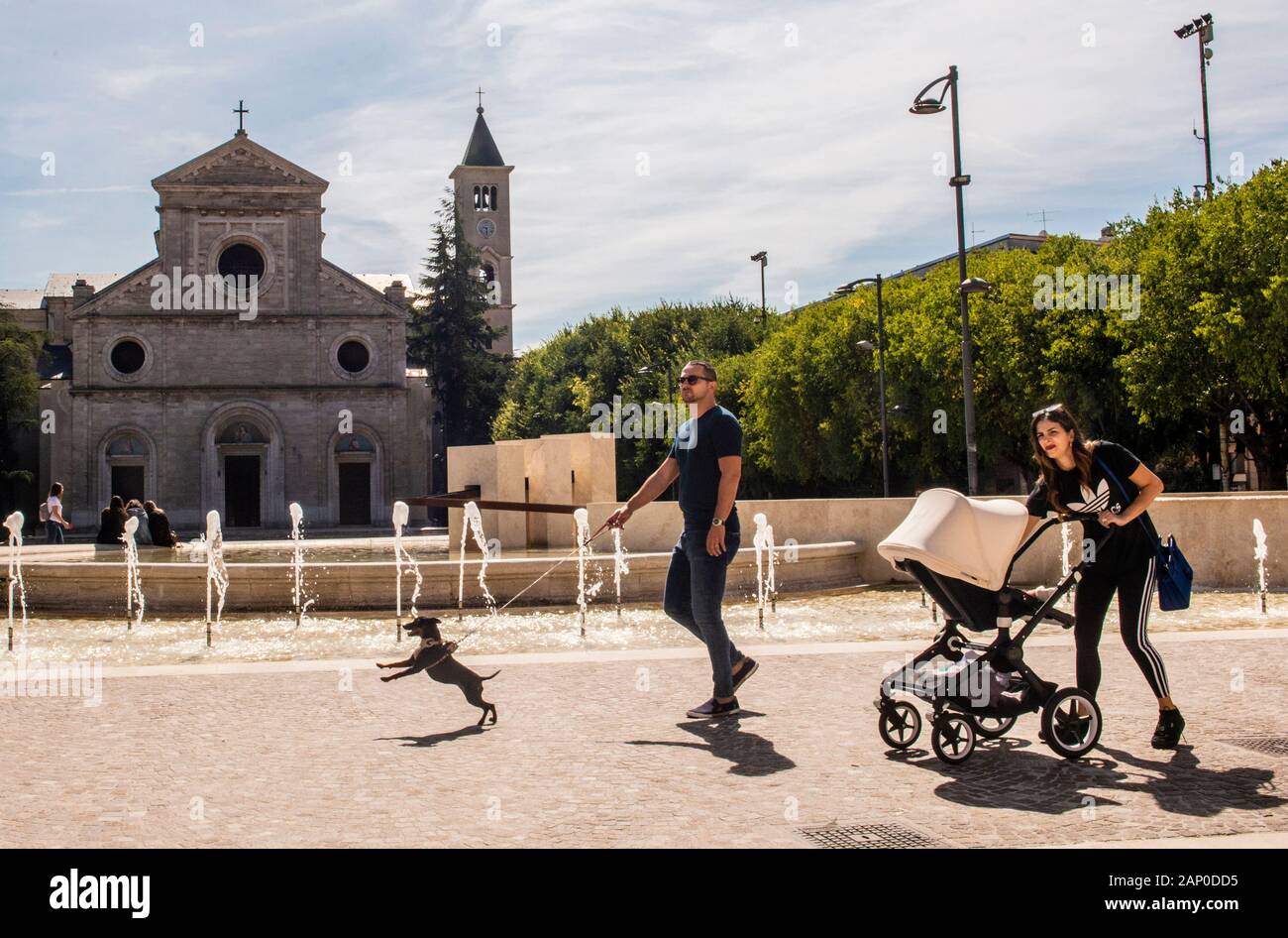 Eltern mit Baby und Hund vorbei gehen. Kirche in Avezzano in den Abruzzen, Italien. Stockfoto