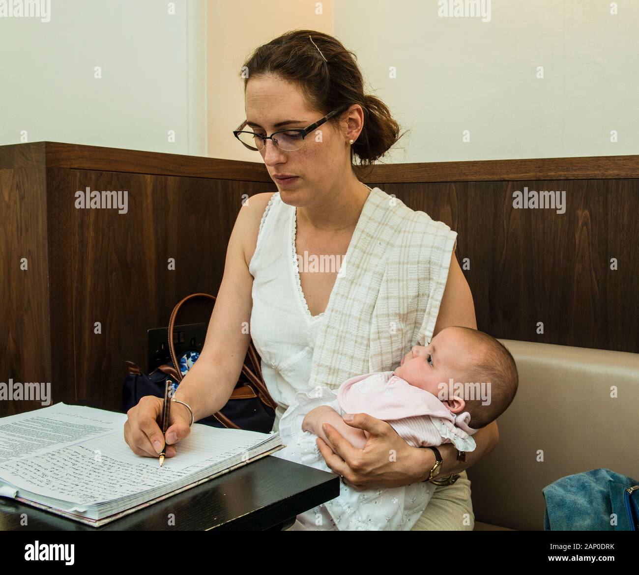 Frau mit Baby und Schreiben im Notebook. Stockfoto