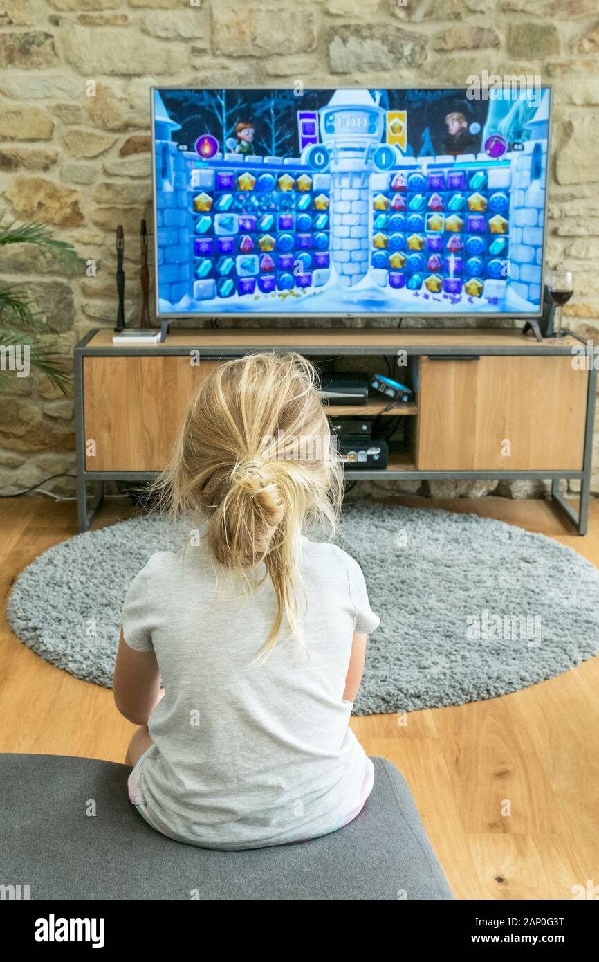 Ein fünf Jahre altes Mädchen spielen ein Spiel auf einem großen Bildschirm. Stockfoto
