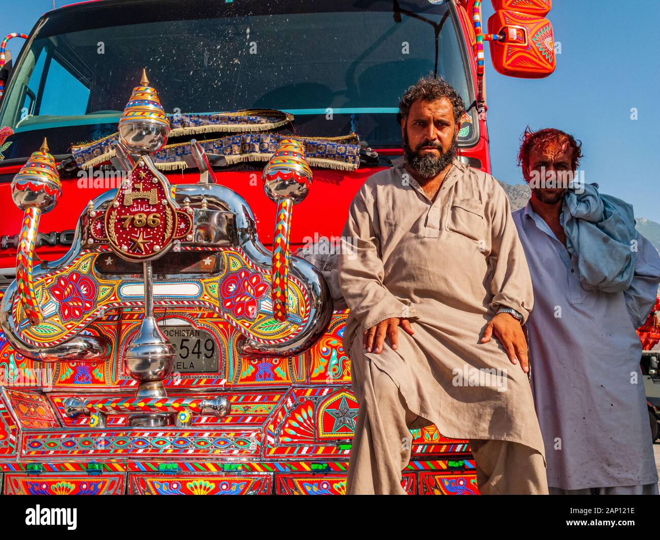 Farbenfroh dekorierte und lackierte LKWs fahren auf den staubigen Straßen des Karakorum Highway, Porträt eines Fahrers Stockfoto