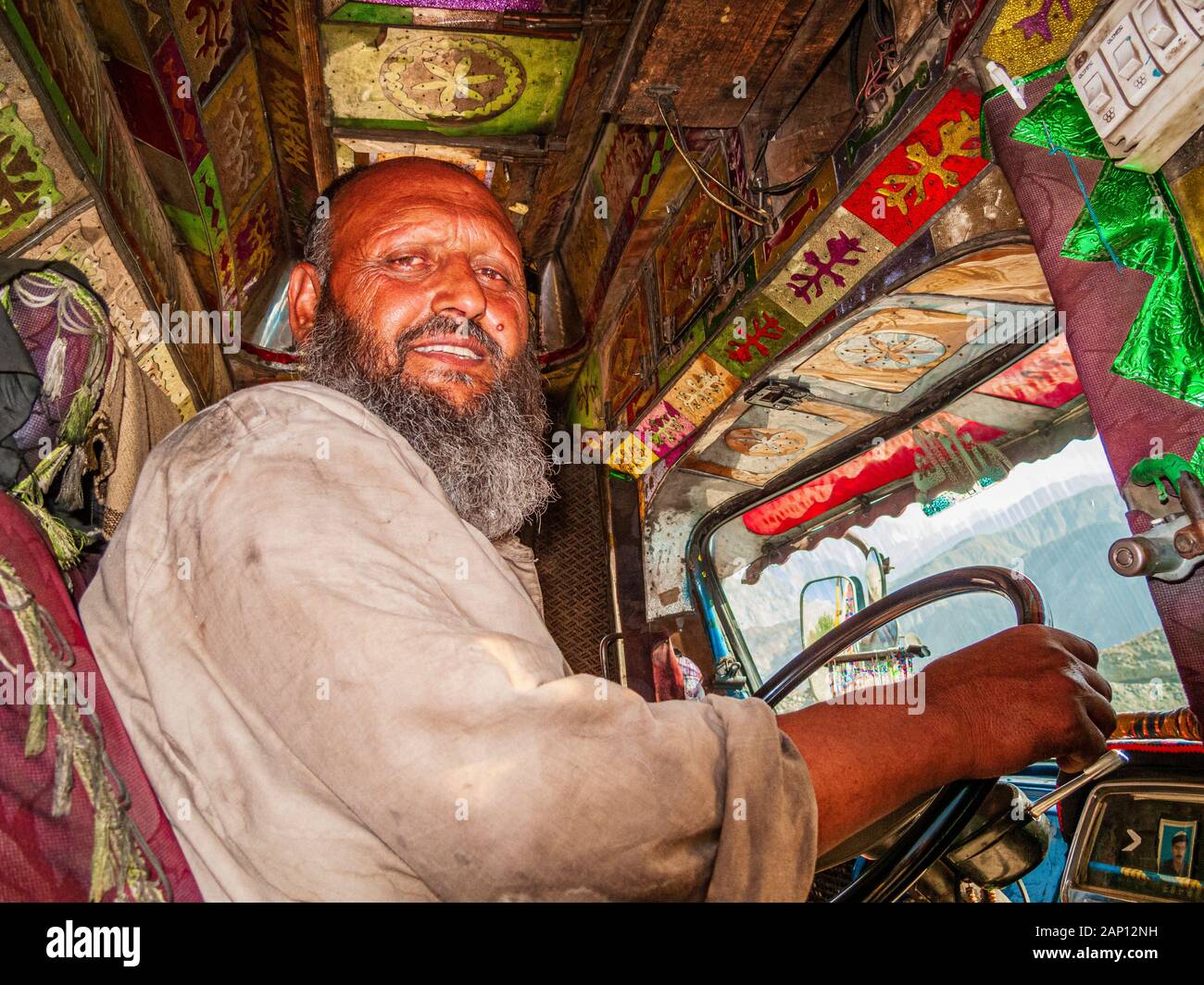 Blick in die Kabine eines farbenfroh dekorierten und lackierten Staplers, auf den staubigen Straßen des Karakorum Highway, Fahrer im Inneren Stockfoto