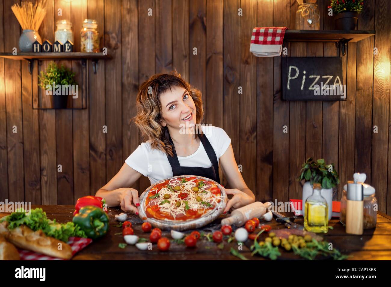 Glückliche Frau kochen Pizza zu Hause Küche aus Holz. Stockfoto