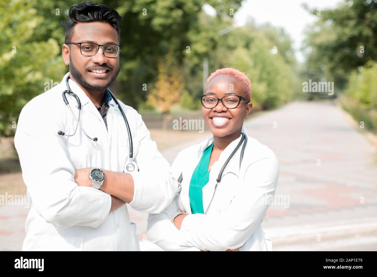 Porträt der jungen Ärzte. Indische Kerl, schwarze Mädchen. Menschen in weißen Kitteln, Gläser, mit stethoskope. Im Freien Stockfoto