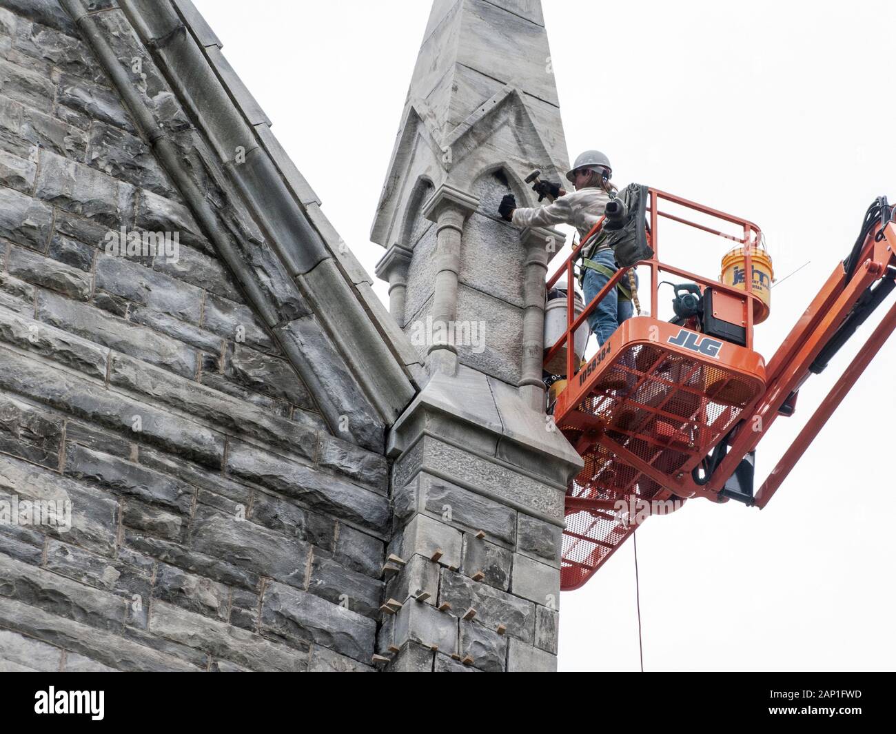 Ein Handwerker Reinigung der Außenseite einer steinernen Kirche Stockfoto