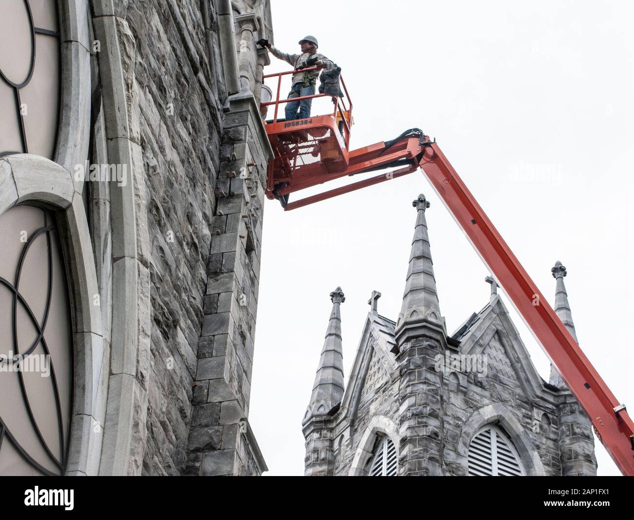 Ein Handwerker Reinigung der Außenseite einer steinernen Kirche Stockfoto