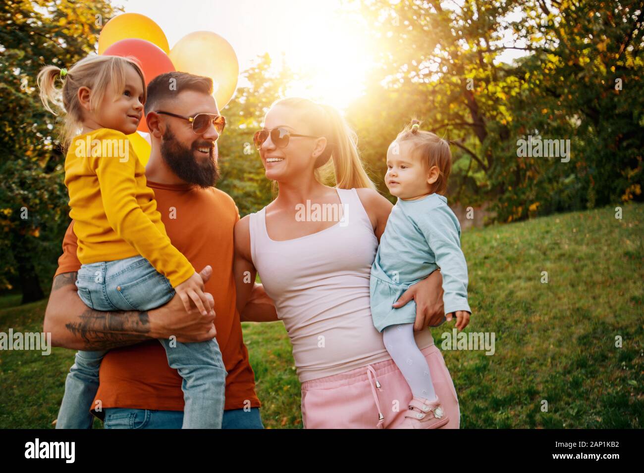 Fröhliche Familie im Urlaub, die draußen genießt. Sie gehen bei Sonnenuntergang im Park. Stockfoto