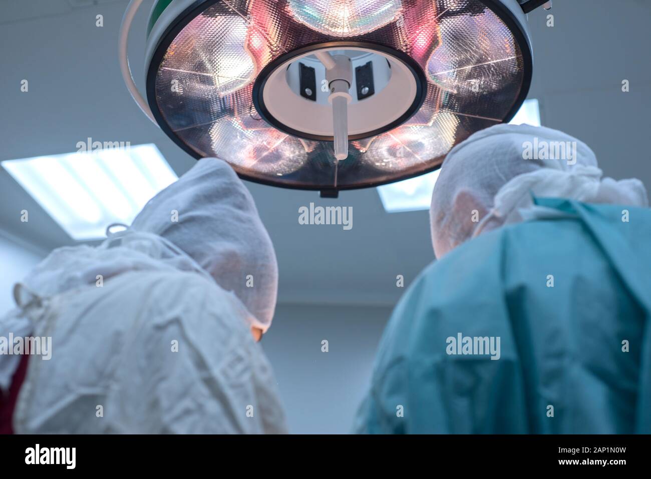Niedrigen Winkel, Pädiatrie, Chirurgie, Chirurgen durchführen, die in einem sterilen Op. Der Blick von der Rückseite. Leuchtet das Feld Lampe. Ärzte profe Stockfoto