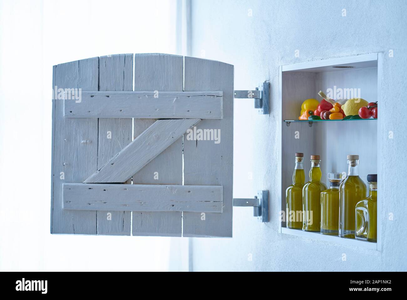 Modernes Wohnzimmer mit Verschluss, kleinem Regal an der Wand mit Flaschen Olivenöl und Gemüse Tomaten Zitronenpaprika und Knoblauch, altes Haus Stockfoto