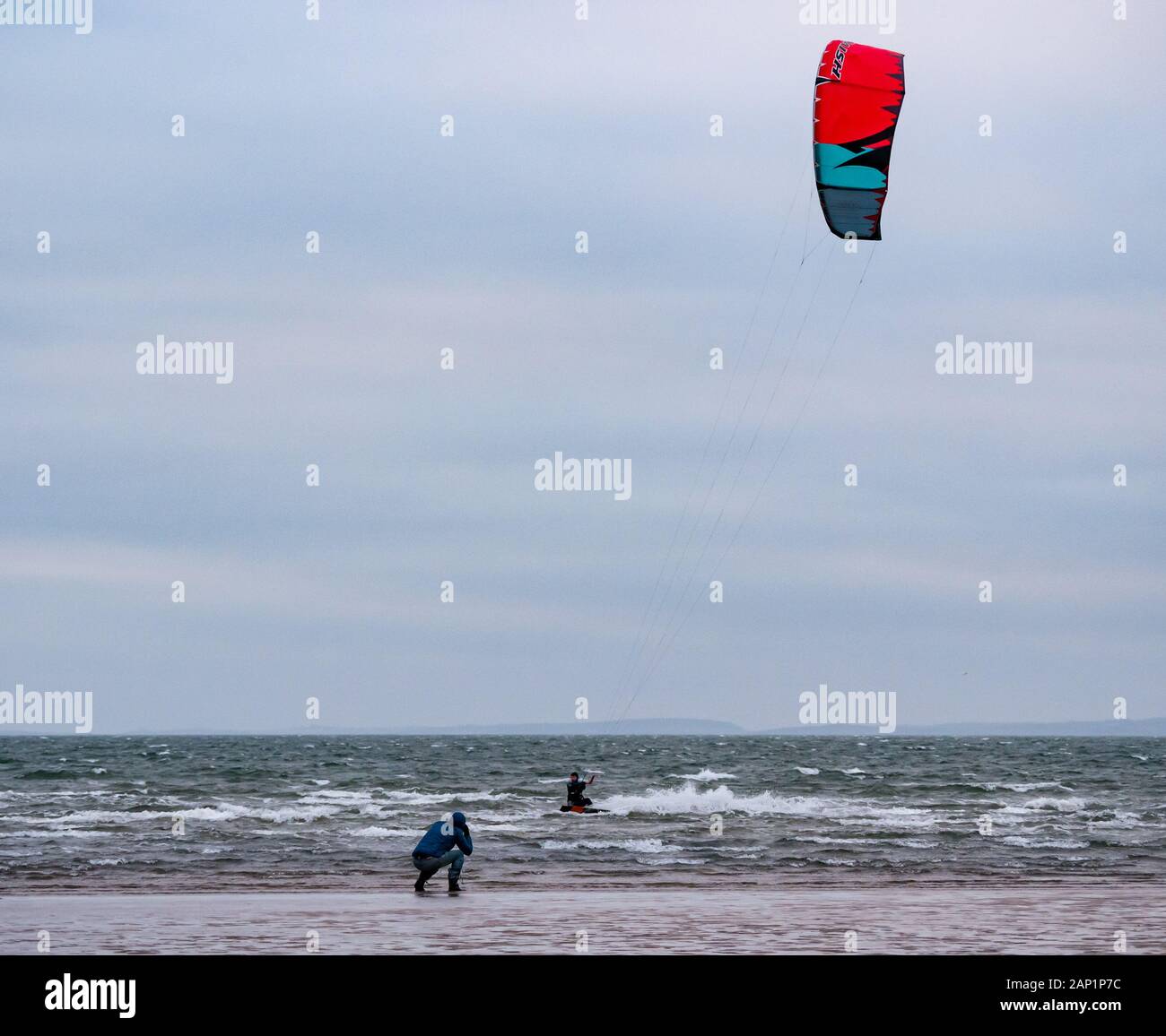 Longniddry Bents, Firth of Forth, East Lothian, Schottland, Großbritannien, 20. Januar 2020. Wetter in Großbritannien: Kitesurfer genießen die steife Brise an einem kalten, windigen Nachmittag bei Ebbe. Ein Mann macht Fotos von den Surfern Stockfoto