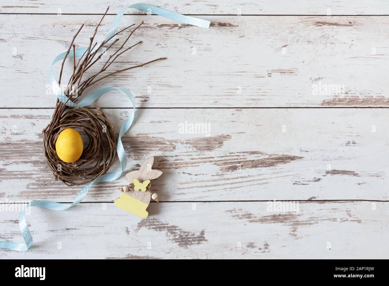 Gelb Osterei auf kreative Nest mit Band auf Holztisch, Ansicht von oben. Frohe Ostern. Kreative Osterdekoration. Kopieren Sie Platz. Stockfoto