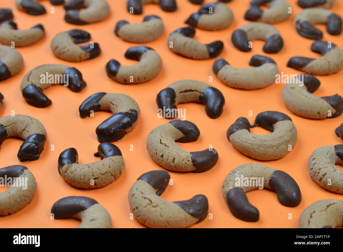 Hausgemachte Nougat Crescent Plätzchen mit Schokolade an den Rändern auf orangefarbenem Hintergrund Stockfoto