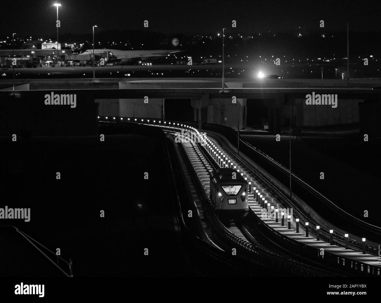 South Airport AUTOMATED PEOPLE MOVER (APM) und Flugzeuge am Orlando International Airport nachts. Stockfoto