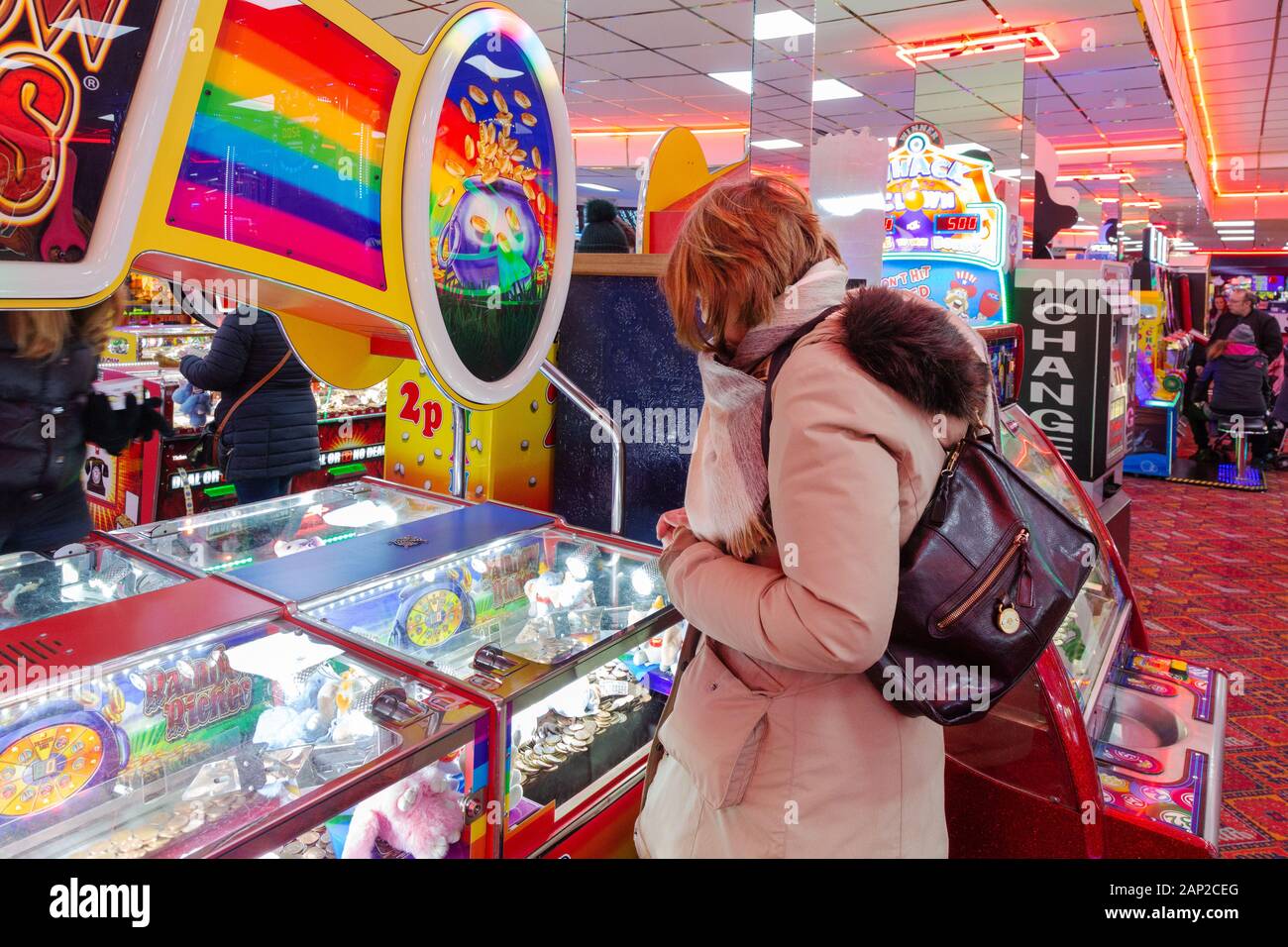 Spielhalle UK - eine Frau, die auf den Münzen oder Spielautomaten in der Vergnügungsparkade, Skegness Lincoln, UK, spielt Stockfoto