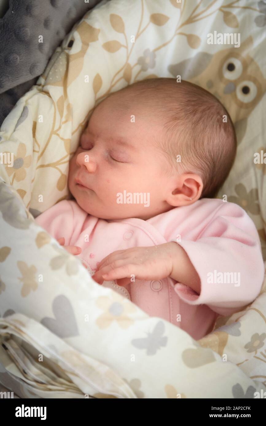 Schlafendes Neugeborenes. Süßes kleines Mädchen, eine Woche alt. Schmückendes liegen auf der mit Decke überzogenen Seite. Stockfoto