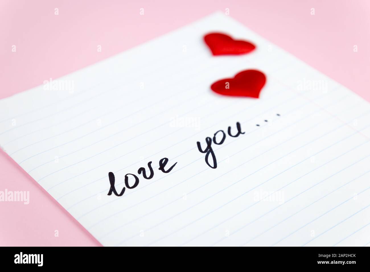 Weibliche Hand schreibt eine Liebeserklärung auf Papier Stockfoto