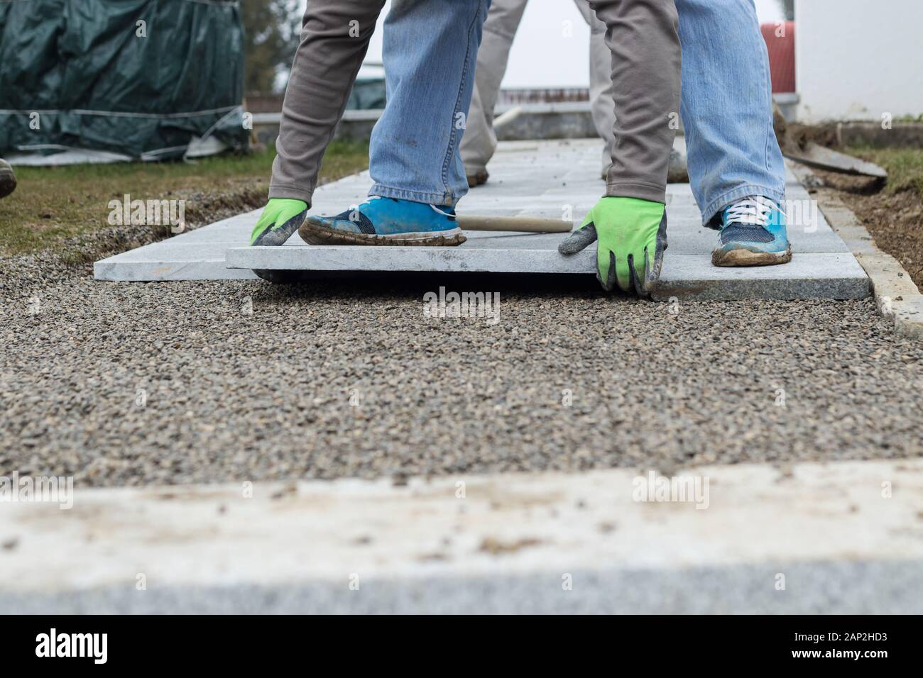Arbeitnehmer legen die Steinplatten auf Schotter Fußweg am Garten zu installieren. Stockfoto