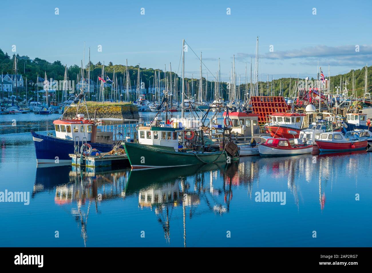 Schönen ruhigen Tag in Tarbert Hafen. Boote Bunte loal und Wasser Reflexionen. Inneren Hebriden in Schottland. Stockfoto