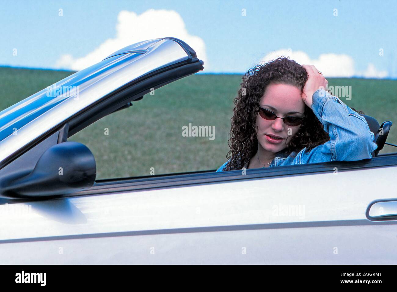 Eine traurige oder nachdenkliche Frau sitzt auf dem Fahrersitz eines wandelbaren Automobil Stockfoto