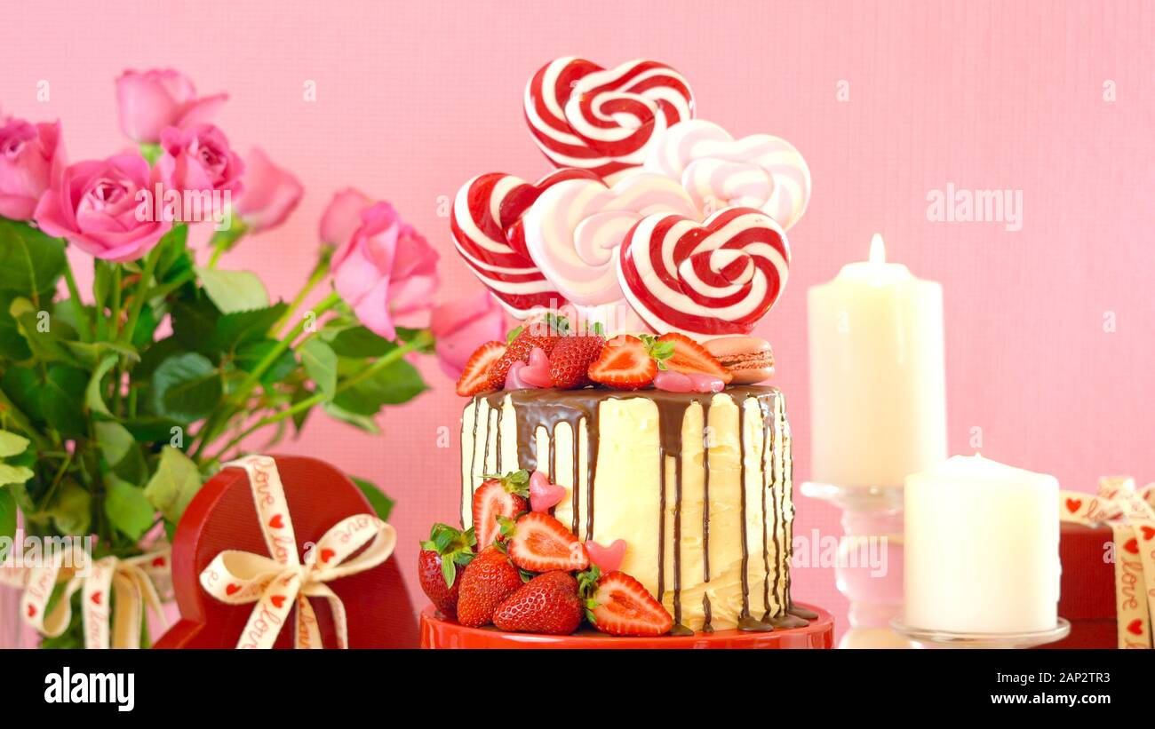 Valentinstag auf - Tendenz candyland Fantasy drip Neuheit Kuchen mit herzförmige Lollis, Candy und frische Erdbeeren dekoriert. Close Up. Stockfoto