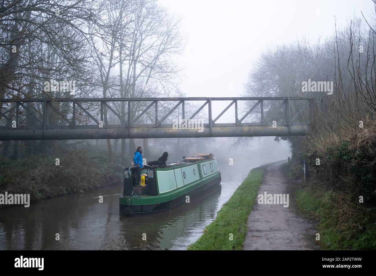 Frau mit zwei Hunden, die das schmale Boot auf Trent und Mersey Kanal in der Nähe von Stoke on Trent, Großbritannien steuern. Stockfoto