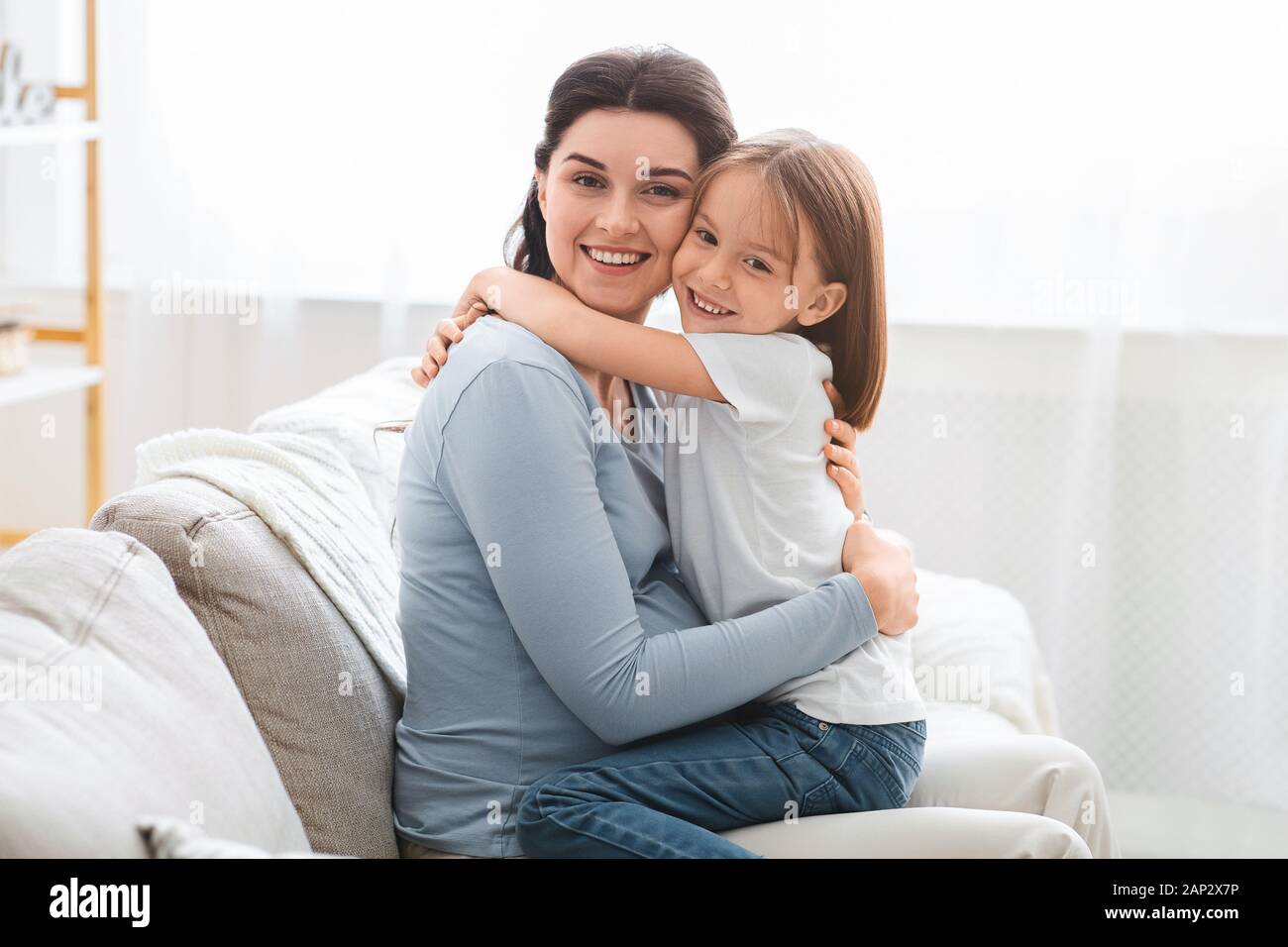 Liebevolle kleine Tochter umarmte ihre Mutter erwartet Stockfoto