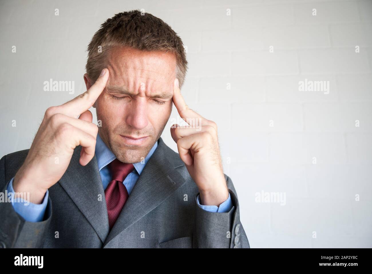 Betonte Geschäftsmann seine Schläfen Reiben mit geschlossenen Augen seine Kopfschmerzen zu lindern Stockfoto