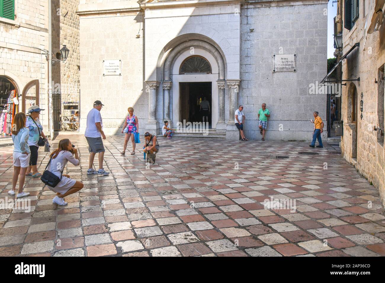 Eine Frau bittet um Hilfe bei der Kirche Schritte als Touristen um eine streunende Katze vor der Kirche St. Nikolaus in mittelalterlichen Kotor, Montenegro sammeln Stockfoto