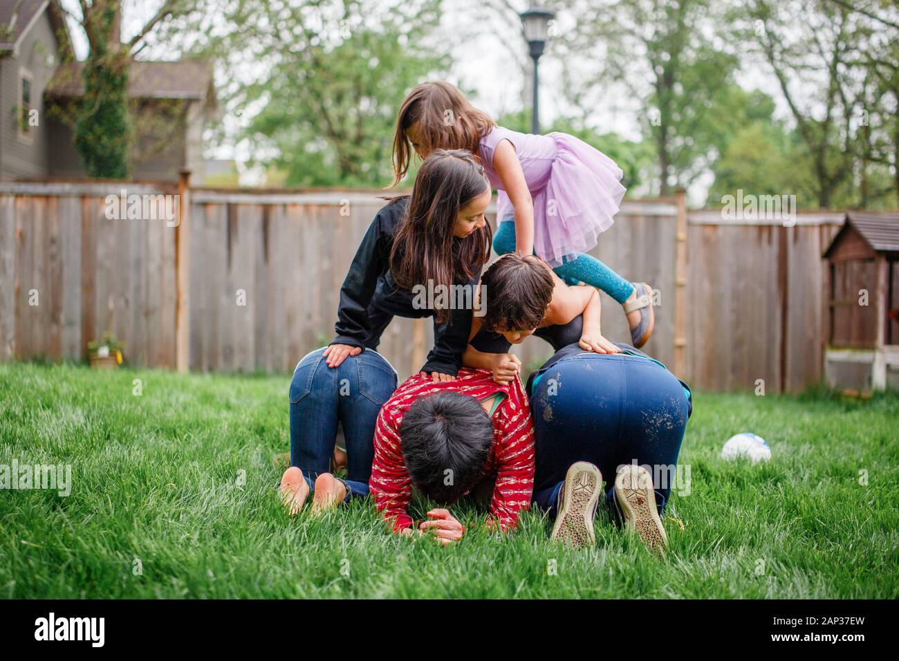 Zwei Erwachsene Brüder bauen eine menschliche Pyramide mit ihren Kindern draußen Stockfoto