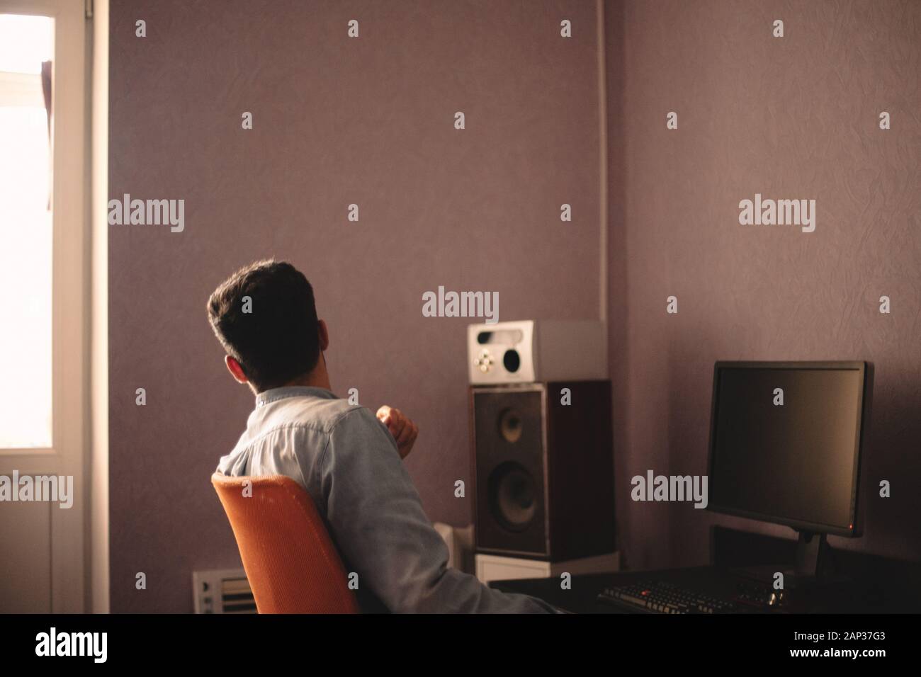 Mann, der durch das Fenster schaut, während er am Desktop-Computer sitzt Stockfoto