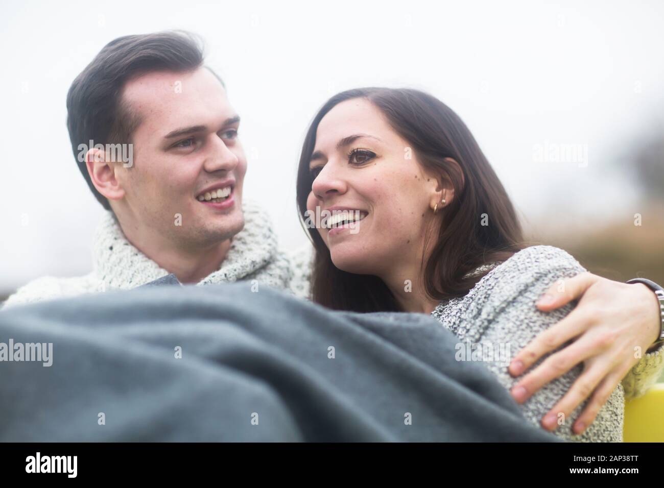 Junges Paar draußen sitzen zusammen in einem Garten Stockfoto