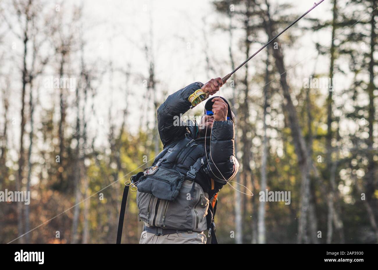 Ein Mann setzt einen Haken beim Fliegenfischen in Maine Stockfoto