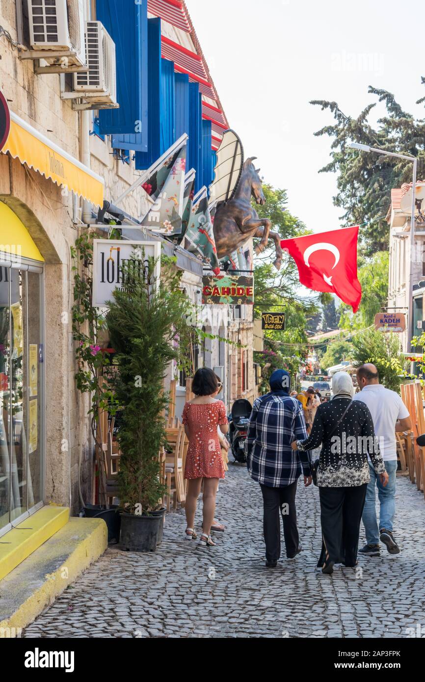 Alacati, Türkei - 4. September 2019: Touristen zu Fuß in einer engen Straße,. Die Stadt ist ein beliebtes Ziel für Touristen. Stockfoto