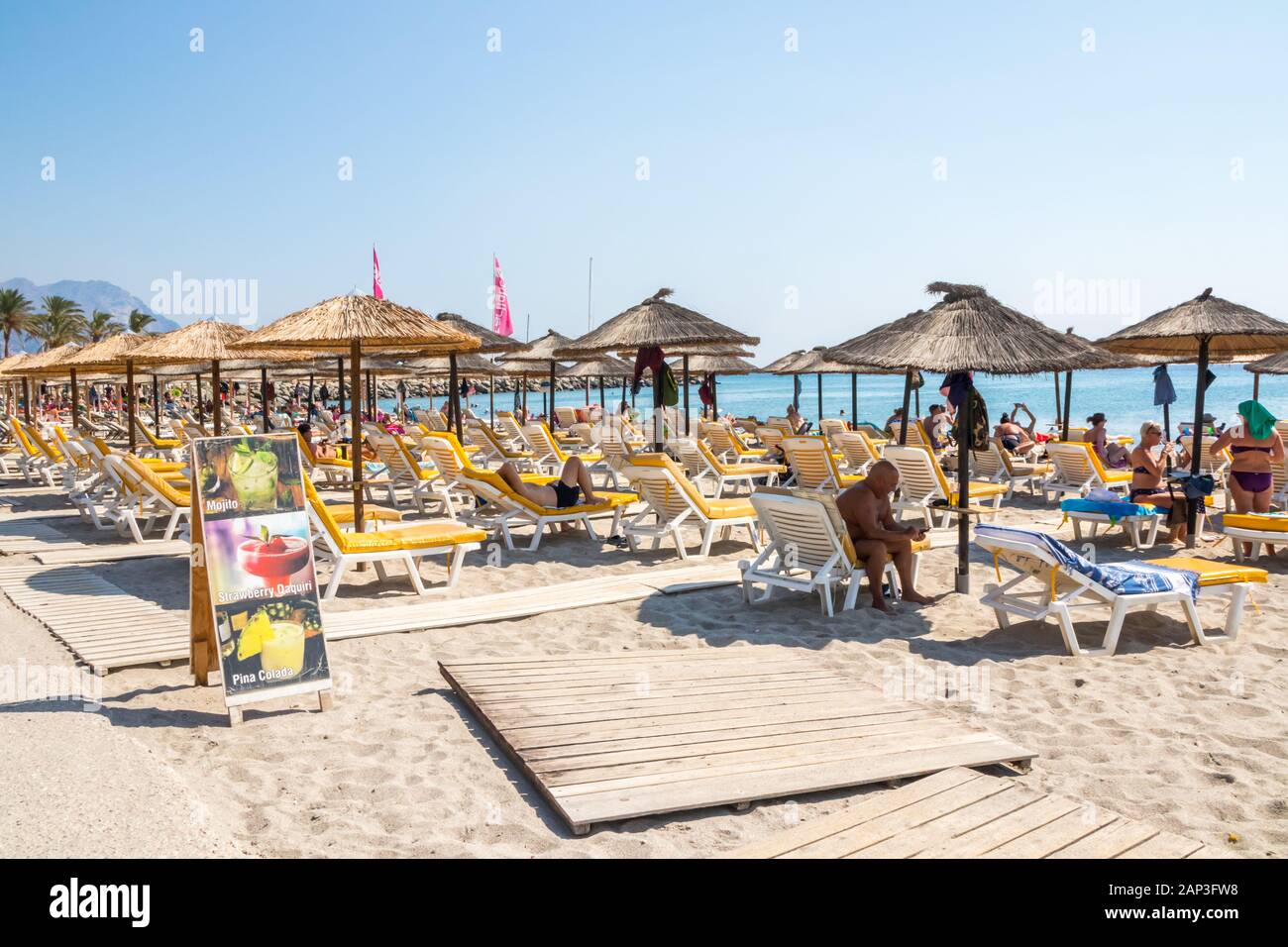 Kardamena an, Kos, Griechenland - 20. September 2019: Menschen auf Liegestühlen unter Sonnenschirmen am Strand der Stadt ist ein beliebtes Urlaubsziel. Stockfoto