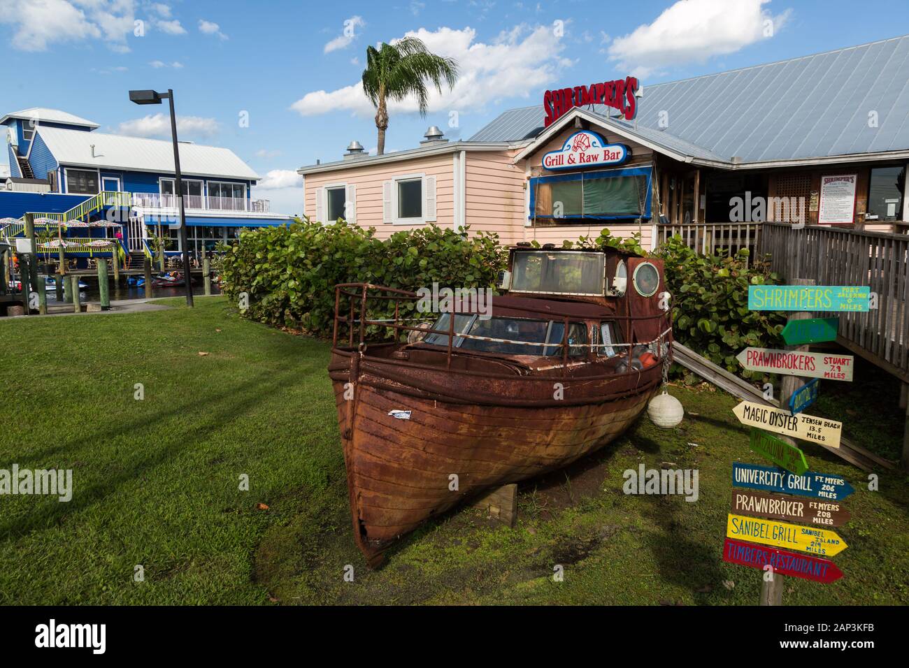 Im Shrimper's Grill and Raw Bar in Port Salerno, Florida, USA, befindet sich ein altes verrostetes Boot auf dem vorderen Rasen. Stockfoto