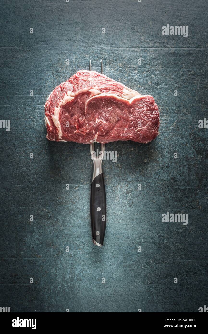 Rohes Rindfleisch Steak mit Gabel auf dunklen konkreten Hintergrund Stockfoto