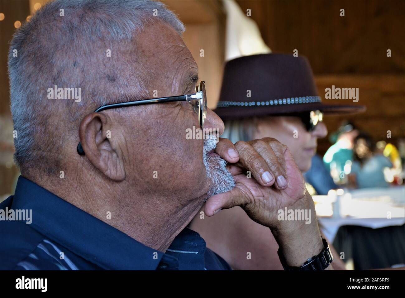 Senior Hispanic Mann bei Familientreffen mit Brille, der denkt das Erfassen Stockfoto