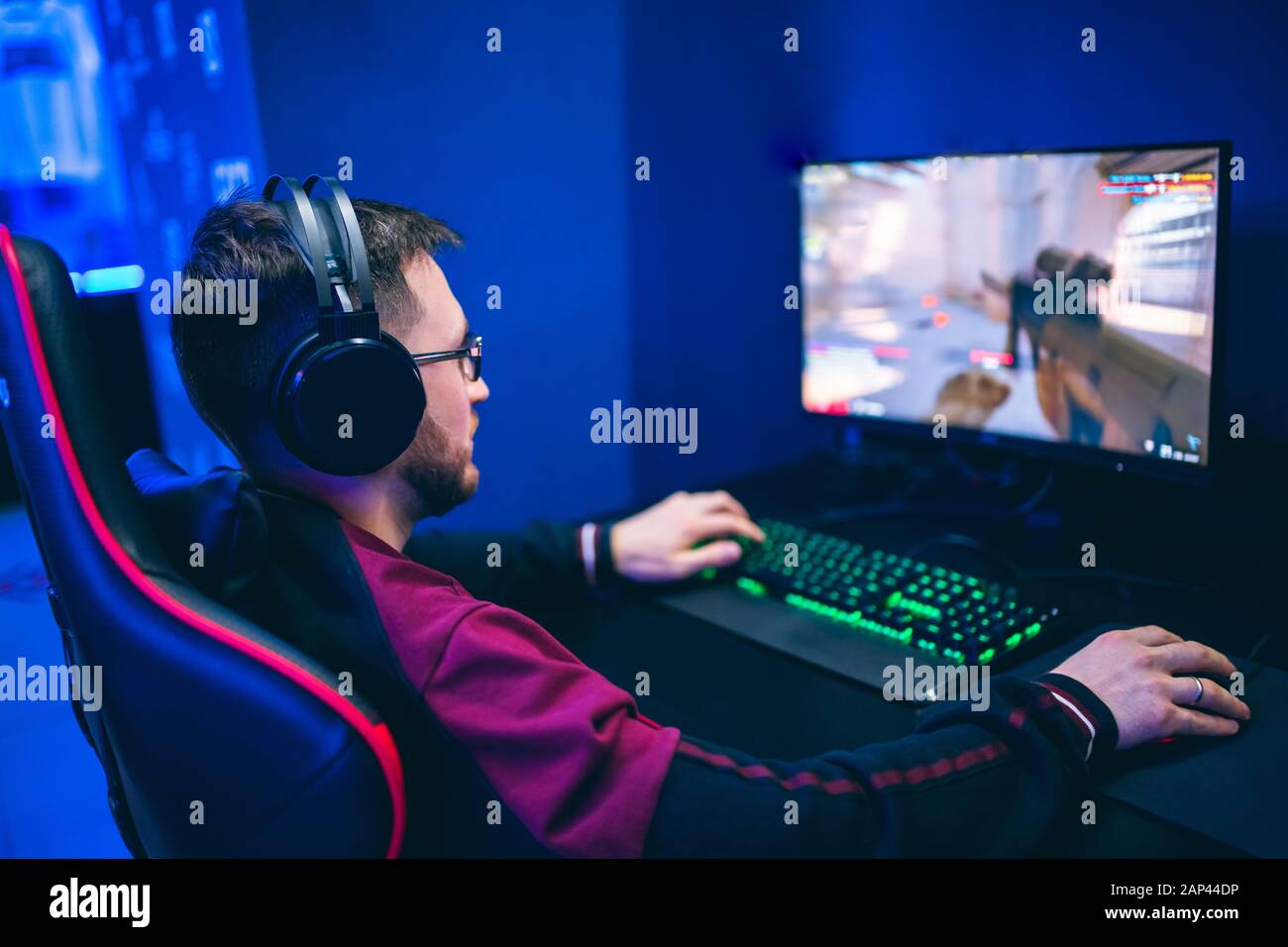 Professionelle Gamer spielen online spiele Turniere pc-Computer mit Kopfhörer, verschwommenes roten und blauen Hintergrund Stockfoto