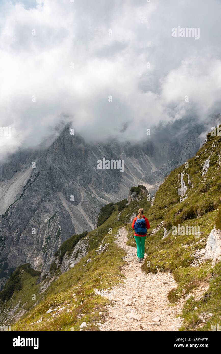Junge Frau, Bergsteigerin auf einem Wanderweg, bewölkter Himmel, Cimon di Croda Liscia und Cadini Group, Sexten Doles, Belluno, Italien Stockfoto