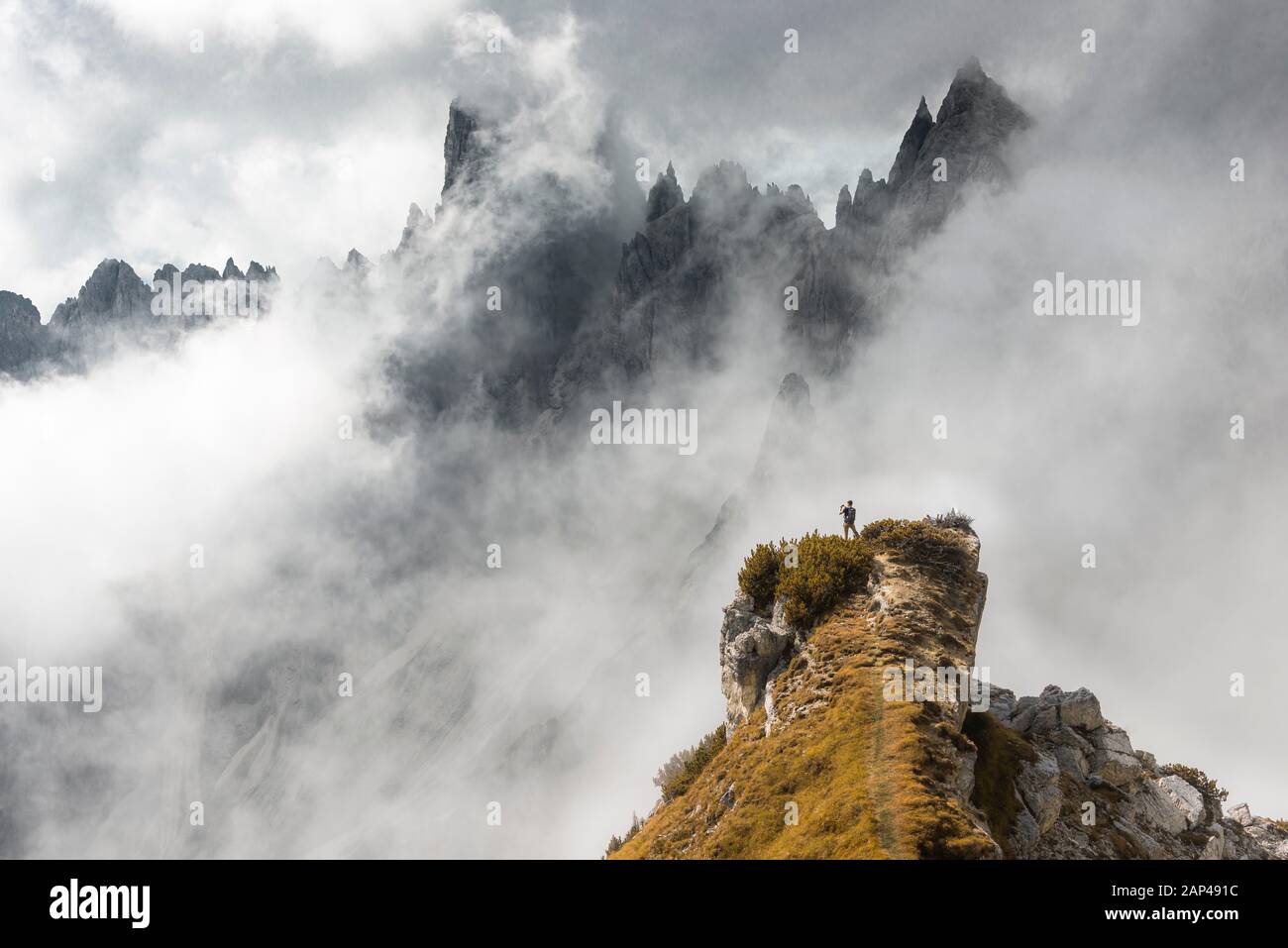 Mann auf einem Bergrücken, hinter Bergkuppen, felsiger Bergrücken mit scharfen Felsspitzen, dramatischen Wolken, Cimon di Croda Liscia und Cadini Group, Sesto Stockfoto