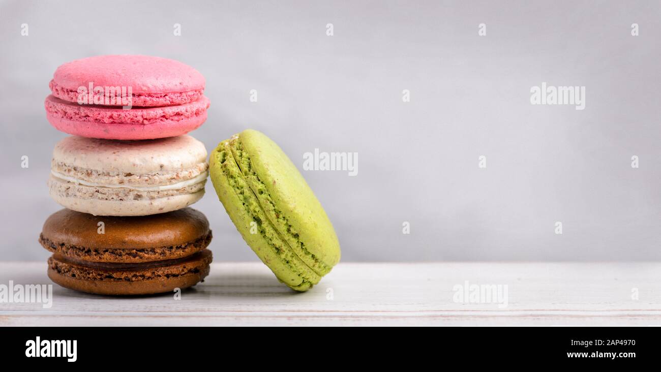 Farbenfrohe Makaron-Plätzchen im Retro-Pastell auf Vintage-Hintergrund mit Copyspace. Hausgemachtes französisches Makaron-Dessert mit verschiedenen Geschmacksrichtungen: Schokolade, Erdbeb Stockfoto