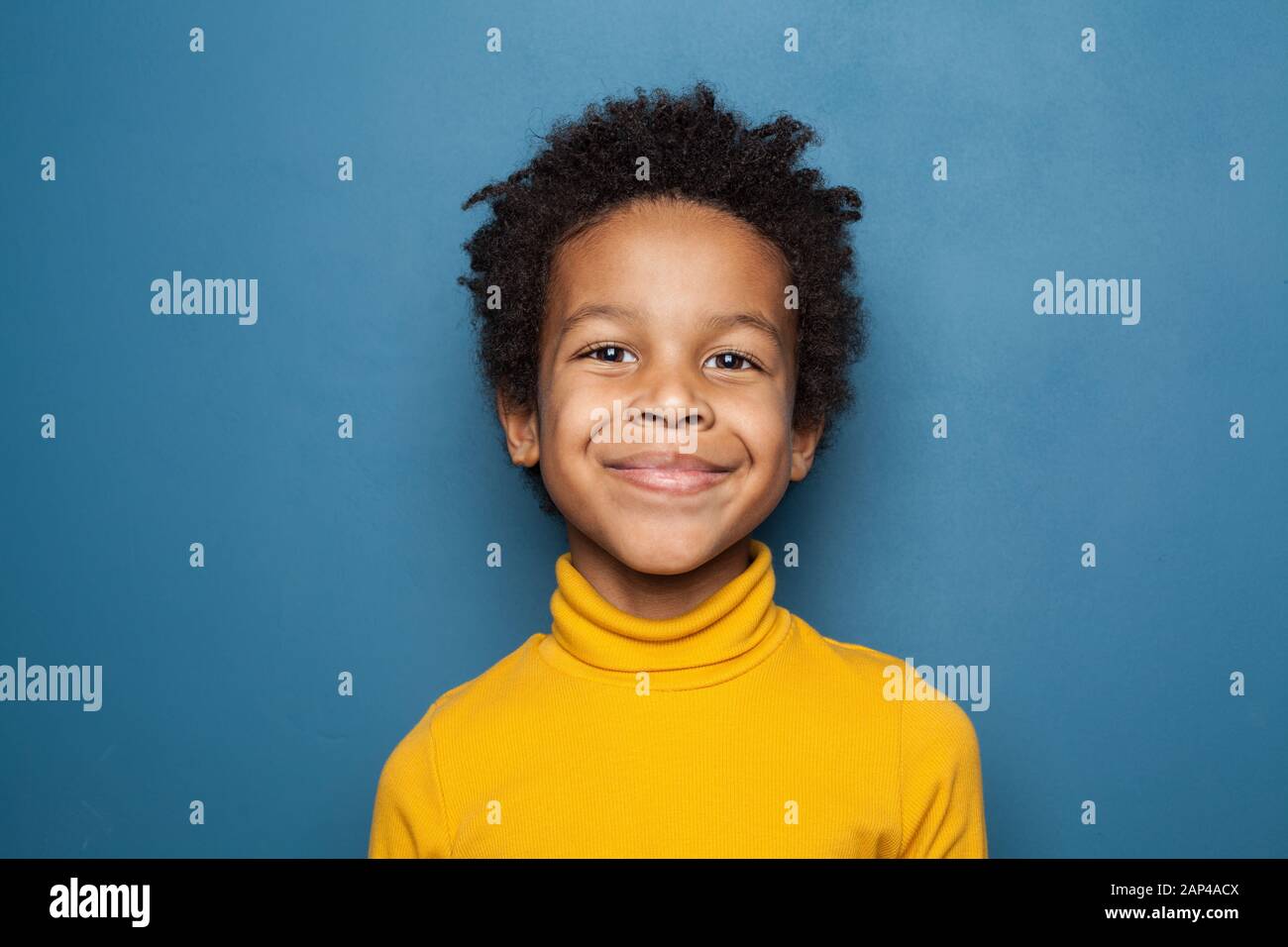 Fröhliches Kinderporträt. Kleiner afroamerikanischer Junge auf blauem Hintergrund Stockfoto