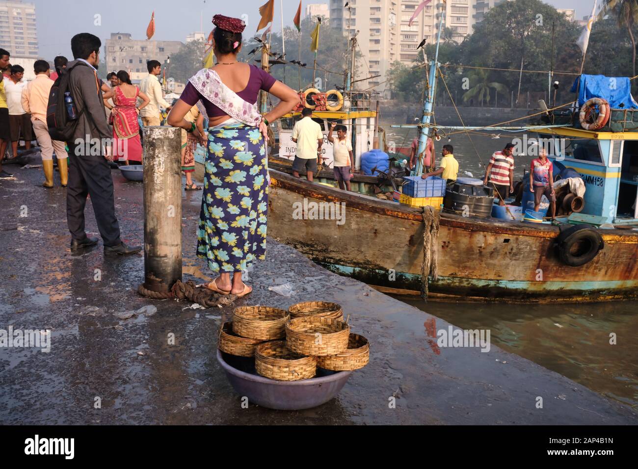 Eine Fischverkäuferin der Koli-Ethnie an den Sassoon Docks, einem Fischerhafen im Colaba-Gebiet, Mumbai, Indien, Fischkörbe im Vordergrund Stockfoto
