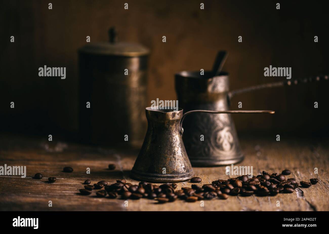 Alte Kaffeekanne und Kaffeebohne auf rustikalem Holztisch. Klassischer orientalischer Kaffee auf dunklem Hintergrund. Stillleben. Stockfoto