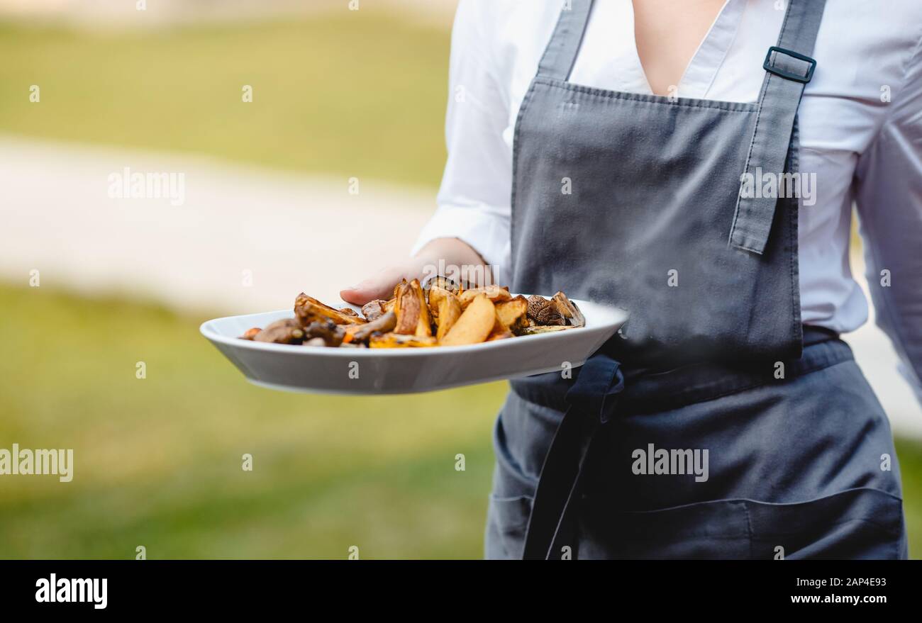 Catering-Service. Der Kellner in der Schürze trägt Imbisse auf der Platte Stockfoto