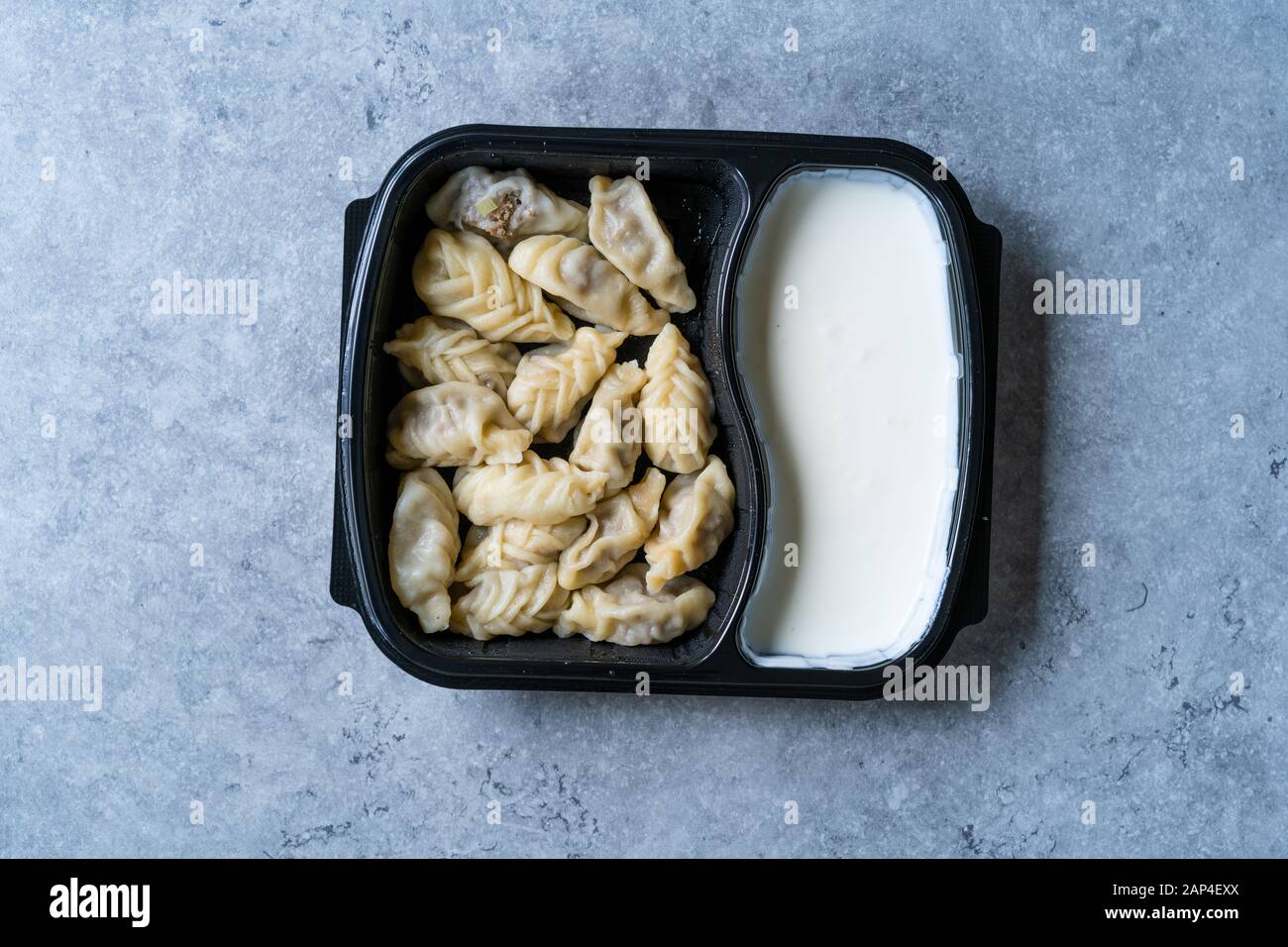 Nehmen Sie den georgischen Knödel Khinkali mit Fleisch, Tomaten, Gewürze und Joghurt in Kunststoff Box Container Paket/Hingel. Bereit zu Essen. Stockfoto