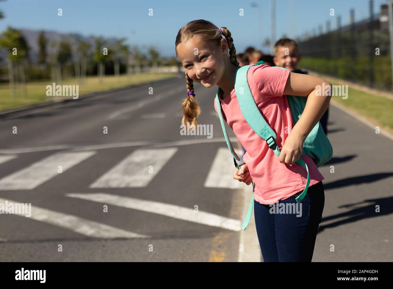 Schulmädchen sucht auf der Suche nach Verkehrsbehinderungen, während sie auf die Straße wartet Stockfoto