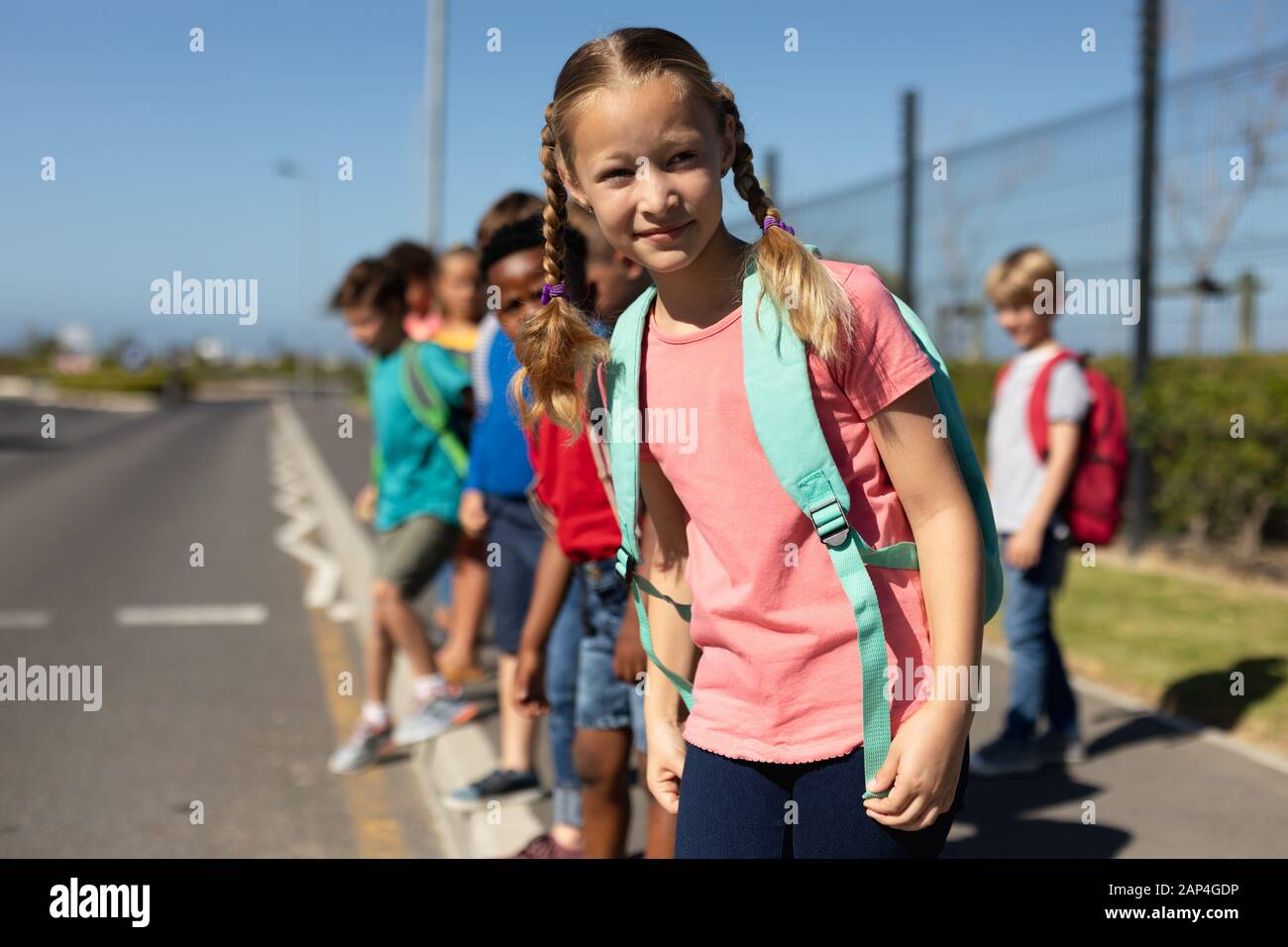 Schulmädchen sucht auf der Suche nach Verkehrsbehinderungen, während sie auf die Straße wartet Stockfoto